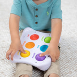 A child explores sensory learning with the colorful Dimpl Duo by Fat Brain Toy Co, promoting tactile engagement on a soft surface.