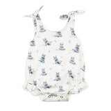 White baby romper from Lovedbaby, with hippo print, tie straps, and ruffled legs. Made of organic cotton.