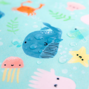 Close-up of water droplets on a Bumkins SuperBib® and Sleeved Bib 3-Piece Set: Rolling With The Waves, Whale Tail, Ocean.