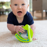 A baby crawls on the carpet in a navy outfit, holding Tobble Tones by Fat Brain Toy Co—a sensory and fine motor toy.