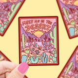 A hand holds Turtle Soups Meet Me in the Desert vinyl sticker showing desert scenery and cacti, surrounded by blurred duplicates.