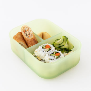 A bento box from Bumkins Lunchbox Legends 6-Piece Set: Motley Green Jelly with sushi and egg rolls sits on a white background.