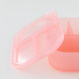 Close-up of Bumkins Silicone Bento Box 3 Section: Pink Jelly, with its transparent lid, on a white background.