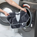 A person holds a Bumkins Sleeved Bib: Jack Skellington in front of an open washing machine.