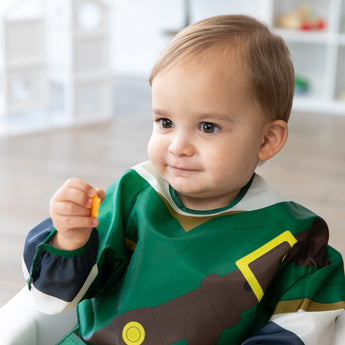 A child in a bib from Bumkins Snack In Character 4-Piece Set: Nintendo Zelda holds an orange cracker.