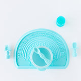 Bumkins Silicone First Feeding Set: Blue sits on a blue placemat on a white background, with blue utensils and a blue cup close by.