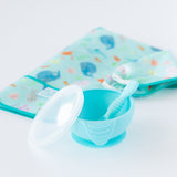 Bumkins Silicone First Feeding Set: Blue sits in front of a folded sea creature-themed bib on a white background.