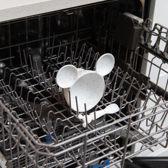 Bumkins Silicone First Feeding Set: Mickey Mouse Vanilla Sprinkle sits in the top rack of an open dishwasher.