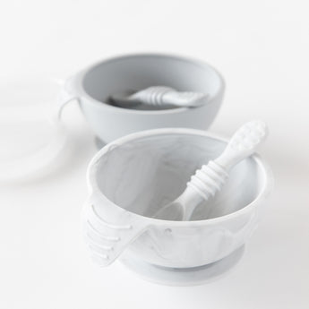 Bumkins Silicone First Feeding Set: Marble sits in front of a gray bowl and spoon set on a white background.