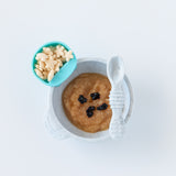 Bumkins Silicone First Feeding Set: Marble with applesauce and berries and a blue cup of star-shaped puffs on a white background.