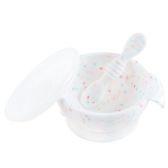 Bumkins Silicone First Feeding Set: Vanilla Sprinkle includes a white speckled bowl with secure suction base, matching spoon, and clear lid.