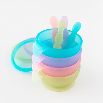 A stack of four colorful bowls and spoons on a white background, featuring Bumkins Silicone First Feeding Set: Blue Jelly on top.