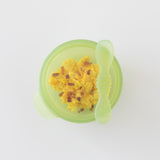 Top down view of Bumkins Silicone First Feeding Set: Green Jelly with yellow scrambled eggs and bacon bits on a white background.