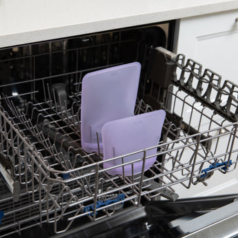 Bumkins Silicone Flat Reusable Bag 2 Pack, Lavender sits in the top rack of an open dishwasher.