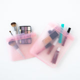 Bumkins Silicone Flat Reusable Bag 2 Pack, Pink holds makeup items on a white background.