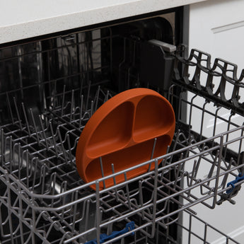 Bumkins Silicone Grip Dish: Clay sits in the top rack of an open dishwasher.