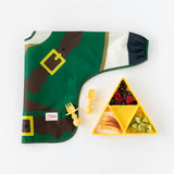 Bumkins Silicone Grip Dish: Zelda™ Triforce with fruit and avocado sits next to a folded bib and yellow baby utensils on a white background.