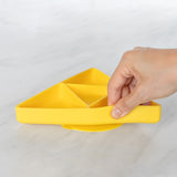 A hand holds a Bumkins Silicone Grip Dish: Zelda™ Triforce, demonstrating the suction cup bottom on a marble surface.
