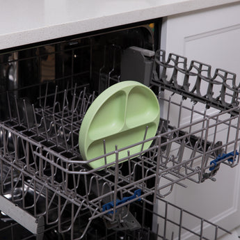 Bumkins Silicone Grip Dish: Sage sits in the top rack of an open dishwasher.