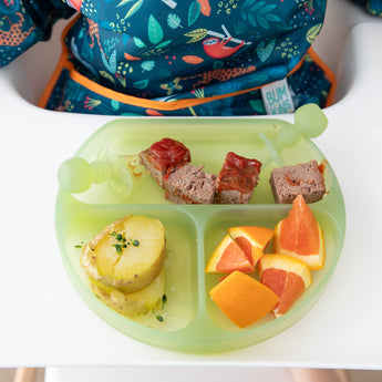 Bumkins Silicone Grip Dish: Green Jelly holds meatloaf, potatoes, and orange wedges with green toddler utensils on a high chair tray.