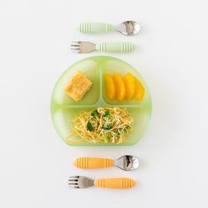 Bumkins Silicone Grip Dish: Green Jelly holding noodles, broccoli, orange slices & bread next to two utensil sets on a white background.