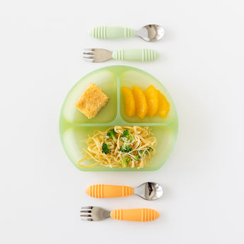 Bumkins Silicone Grip Dish: Green Jelly holding noodles, broccoli, orange slices & bread next to two utensil sets on a white background.