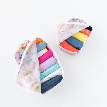 Bumkins Packing Cube 2 Pack: Boots shown open with colorful clothes inside, crafted from waterproof fabric, set against a white background.