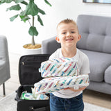 A child holds Bumkins Packing Cube 2 Pack: Mickey & Friends Varsity, standing by an open suitcase in a bright room with a gray couch.