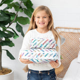 A girl smiles while she holds Bumkins Packing Cube 2 Pack: Mickey & Friends Varsity in her hands.