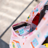 Close-up of Bumkins Packable Tote Bag: Boots with a smartphone in its pocket. Shadows play on the background.