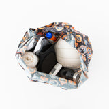 Top view of a Bumkins Packable Tote Bag: Ghostly Gallery containing a volleyball, bottle, towel, shoes, socks & deodorant on a white background.