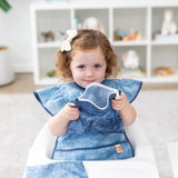 A young girl in a bow looks curiously at the camera with Bumkins Snack In Style 3-Piece Set: Denim On Denim.