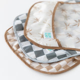 Close-up of Bumkins SuperBib® 3 Pack: Palms + Check stacked on a white background, with focus on the bottom pocket.