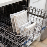 Three Bumkins Reusable Snack Bags (Double Check, 4 Pack) stand upright in the bottom rack of an open dishwasher.