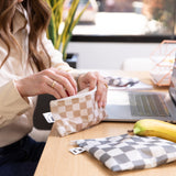 A woman reaches for snacks from Roamio by Bumkins Reusable Snack Bag 4 Pack: Double Check at a desk near a laptop.