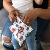 A person with a child on their lap reaches into a Bumkins Reusable Snack Bag, Large: Super Mario™ & Luigi.