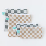 Five reusable zipper bags in various sizes with checkered patterns in gray and beige are arranged on a white background. A small tag with Bumkins is visible on each bag.