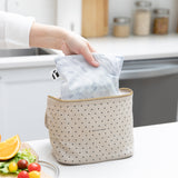 A hand places a Roamio by Bumkins Reusable Snack Bag, Large 2 Pack: Disco Boots into a lunch bag on a counter next to fruit & veggies.