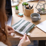 A person unzips a Roamio by Bumkins Reusable Snack Bag, Large 2 Pack: Motley Club at a desk with coffee, a laptop, office supplies, and plants.