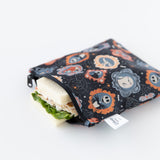 A Bumkins Reusable Snack Bag, Large 2 Pack: Everyday Is Halloween rests on a white background with a sandwich inside.