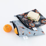 Bumkins Reusable Snack Bag, Large 2 Pack: Everyday Is Halloween sits on a white background with oranges and sandwiches.