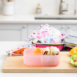 A kitchen counter with Bumkins Lunchbox Legends 6-Piece Set: Watercolor Pink Jelly, lunch bag, cutting board, and fruit & veggies.