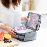 A woman packs a lunch bag with Bumkins Lunchbox Legends 6-Piece Set: Unicorns Purple Jelly on a kitchen counter.