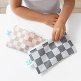 A child sits at a white table, holding Bumkins Reusable Snack Bag, Small 2 Pack: Double Check.