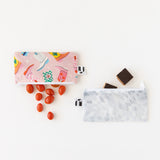 Grape tomatoes and chocolate squares spill from Roamio by Bumkins Reusable Snack Bag, Small 2 Pack: Disco Boots on a white background.