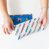 Hands hold Bumkins Reusable Snack Bag, Small 2 Pack: Mickey & Friends MVP at a white table.