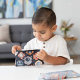 A young boy looks into a Bumkins Reusable Snack Bag, Small 2 Pack: Everyday Is Halloween at a white table in a modern living room.