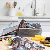 A Bumkins Reusable Snack Bag, Small 2 Pack: Everyday Is Halloween sits in a gray lunch bag on a kitchen counter, surrounded by food.