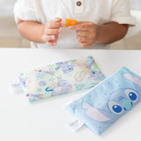 A child holds a cracker above Bumkins Reusable Snack Bag, Small 2 Pack: Stitch Star-ring Up Trouble on a white table.