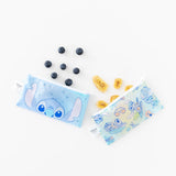 Bumkins Reusable Snack Bag, Small 2 Pack: Stitch Star-ring Up Trouble set on a white background, surrounded by blueberries and banana chips.